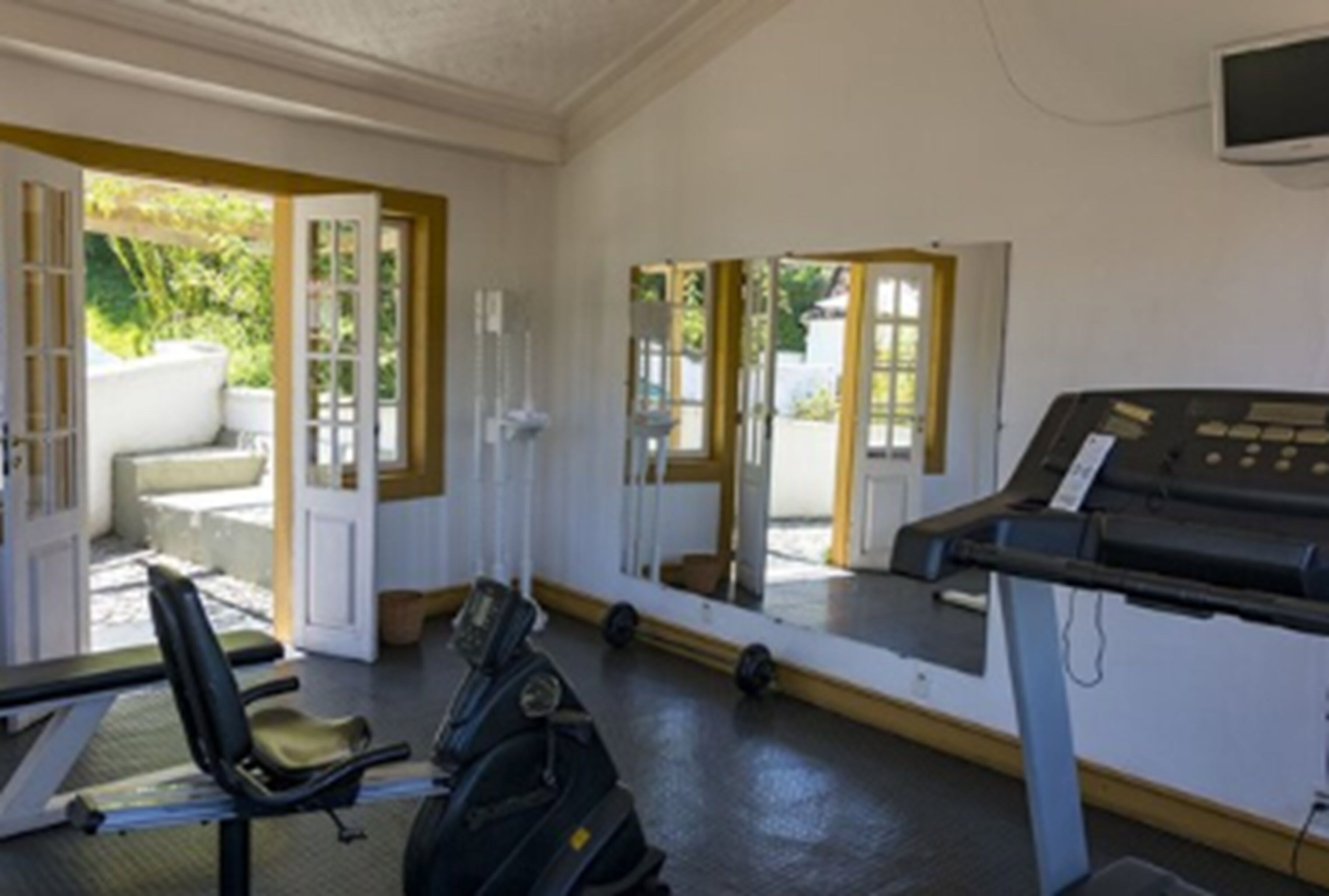 A room with a treadmill, a chair, and a desk with a computer.