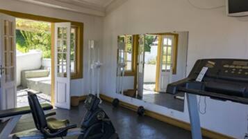 A room with a treadmill, a chair, and a desk with a computer.