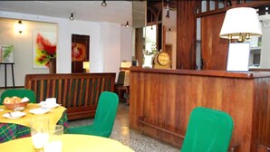 Ein Restaurant mit Holztischen, einer Theke und einem grünen Stuhl.