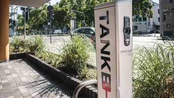 Una estación de carga TANKE en una gasolinera, con una zona pavimentada y áreas verdes cercanas.