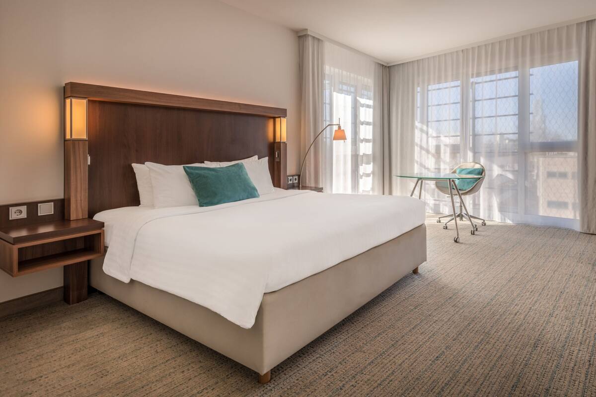 Une chambre d’hôtel avec un grand lit, un bureau et une chaise.