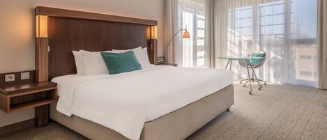 A hotel room with a large bed, a desk, and a chair.