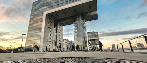 Un bâtiment moderne doté d’une architecture originale, caractérisé par une grande structure en surplomb et de nombreux étages avec de vastes fenêtres en verre.