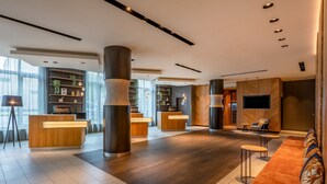 Een moderne lobby met een receptiebalie, een zithoek en grote ramen.