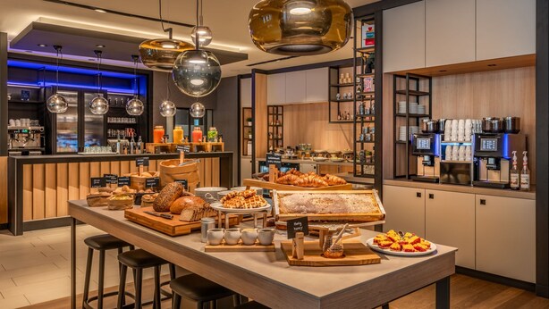 Een modern café met een centrale bedieningsbar, een bar en zitplaatsen.