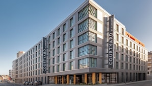 Een modern hotel met een platte gevel, grote ramen en een opvallend 'Courtyard by Marriott' logo.