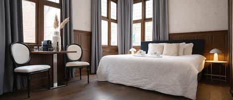 Una habitación de hotel con una cama grande, un escritorio con silla y una ventana con cortinas.