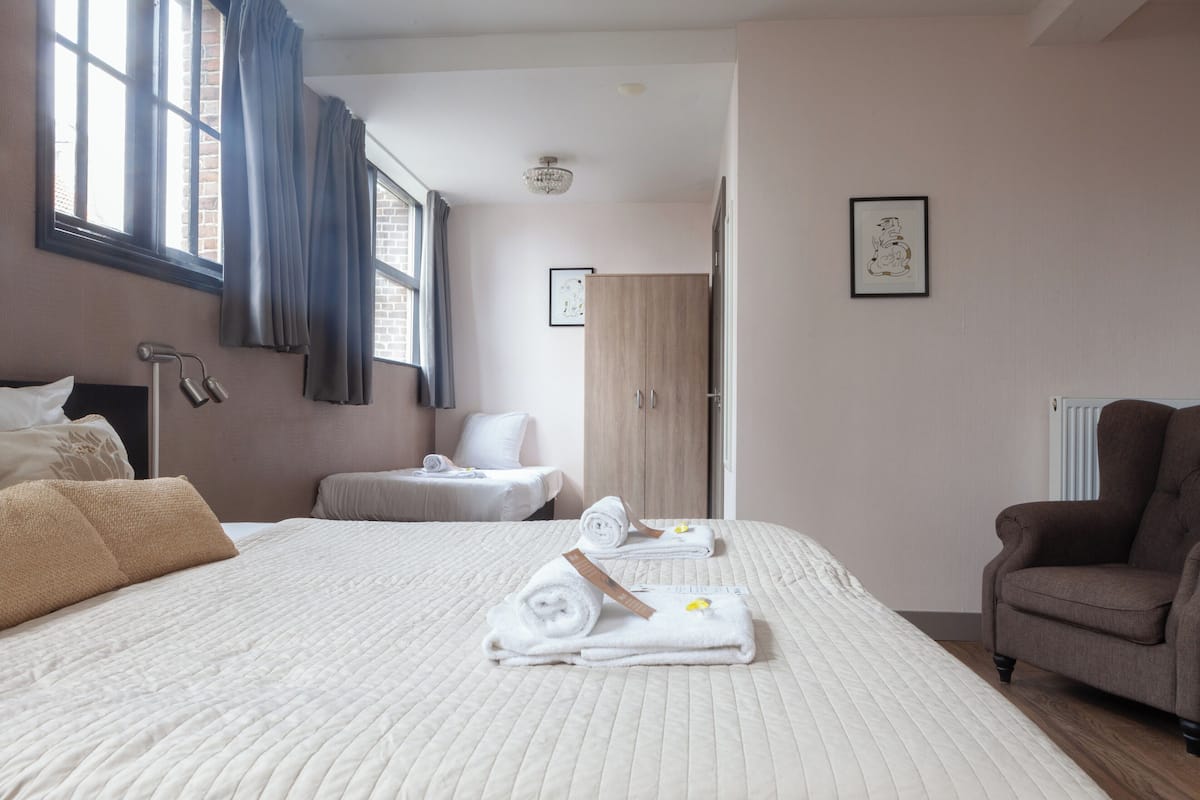 Habitación de hotel con una cama grande, una silla, un escritorio y un armario.