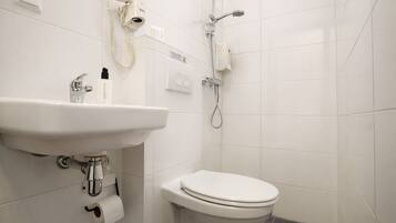 A bathroom with a white sink, toilet, and a handheld showerhead.