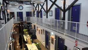 A multi-level hotel lobby with a central staircase, multiple doors, and string lights.