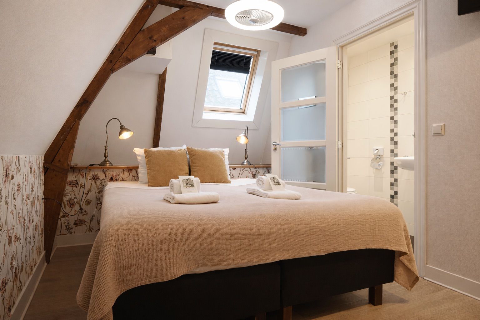 A bedroom with a bed, pillows, a nightstand, a window, and a door.