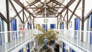 A spacious atrium with high ceilings, wooden beams, and a central seating area.