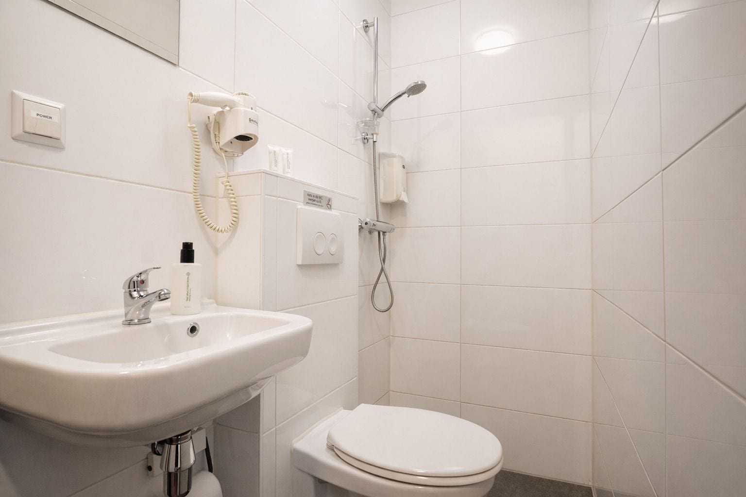 A bathroom with a white sink, a toilet, and a shower.