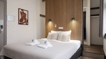 A hotel room with a bed, towels, a wall-mounted artwork, and a wooden panel wall.