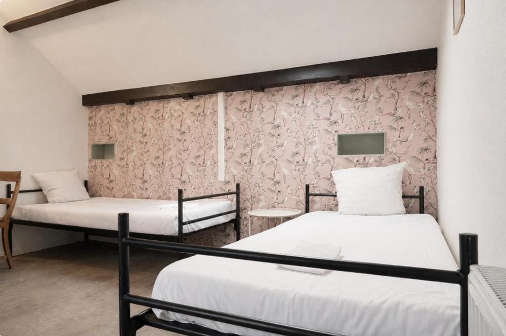 A room with two bunk beds, a small round table, and a chair.