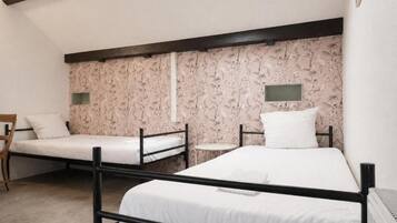 A room with two bunk beds, a small round table, and a chair.