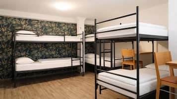 A dormitory room with bunk beds, a wooden chair, and a small table.