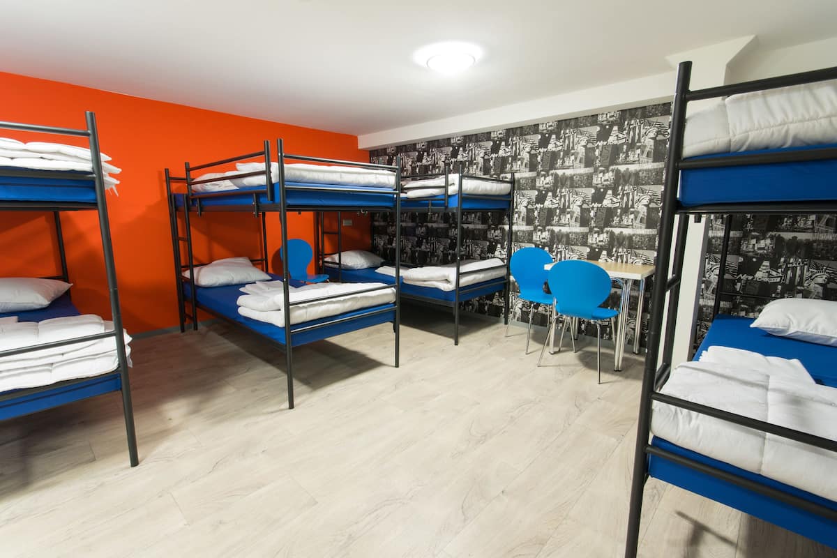 Un dormitorio con literas, un escritorio y sillas.