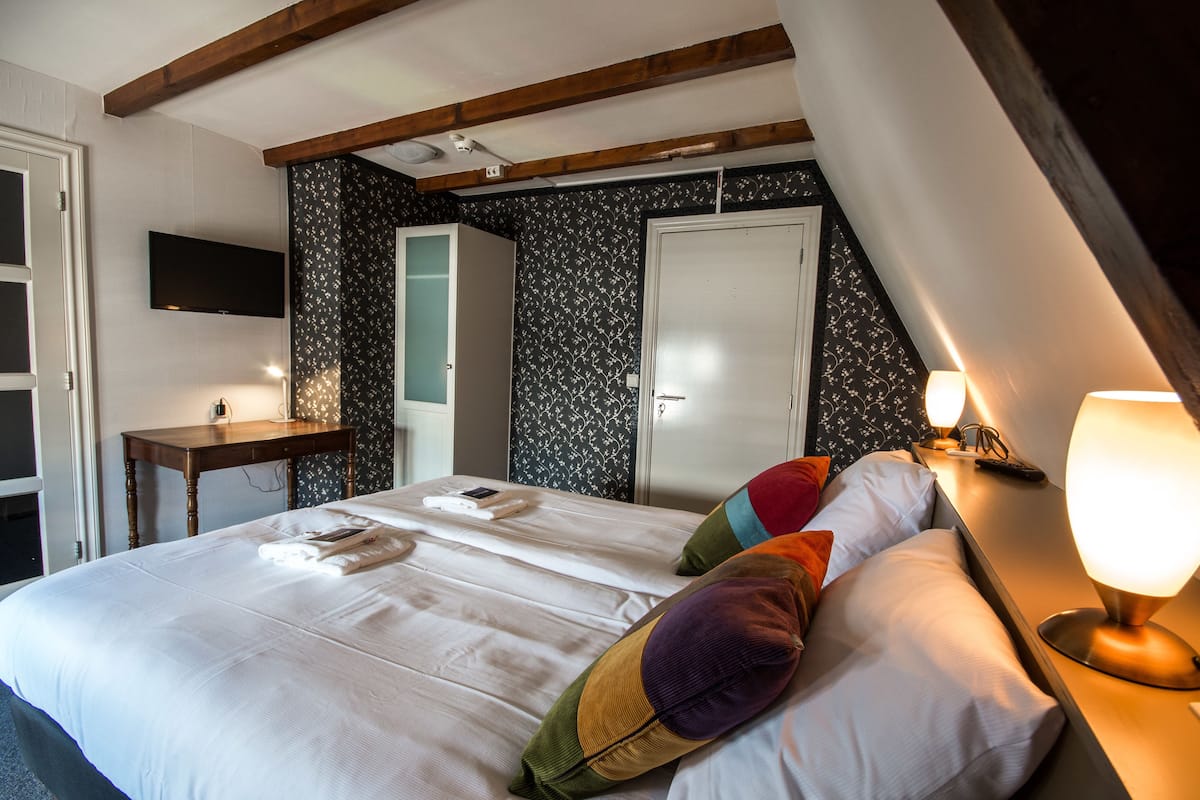 Una habitación de hotel con cama, escritorio, televisor y armario.