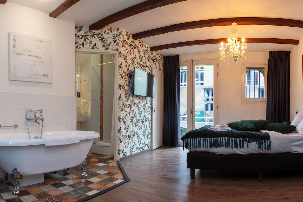 Un dormitorio con una cama grande, una bañera y una ducha.