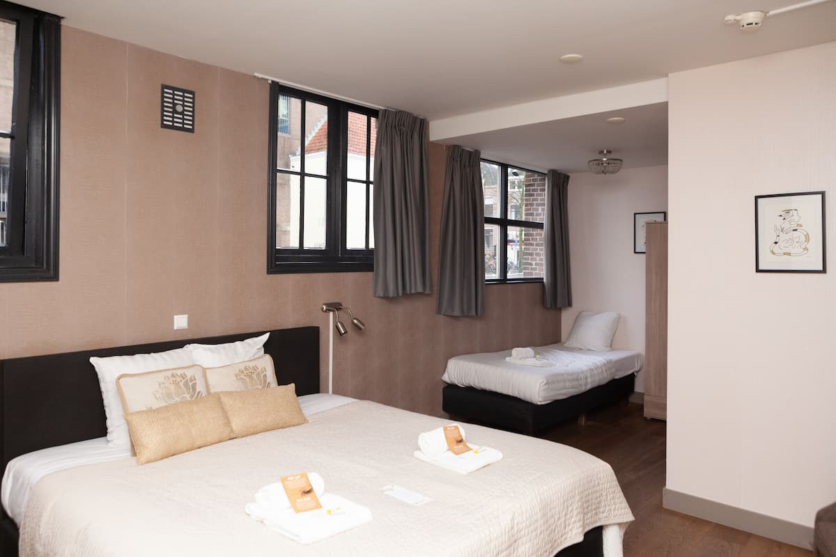Una habitación de hotel con una cama grande, una cama más pequeña y un escritorio.