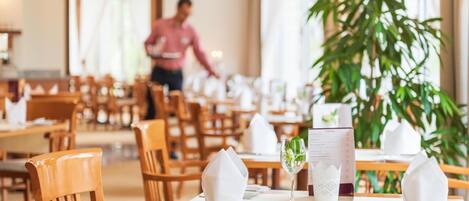 A restaurant setting with wooden tables and chairs, white table settings, and a menu.