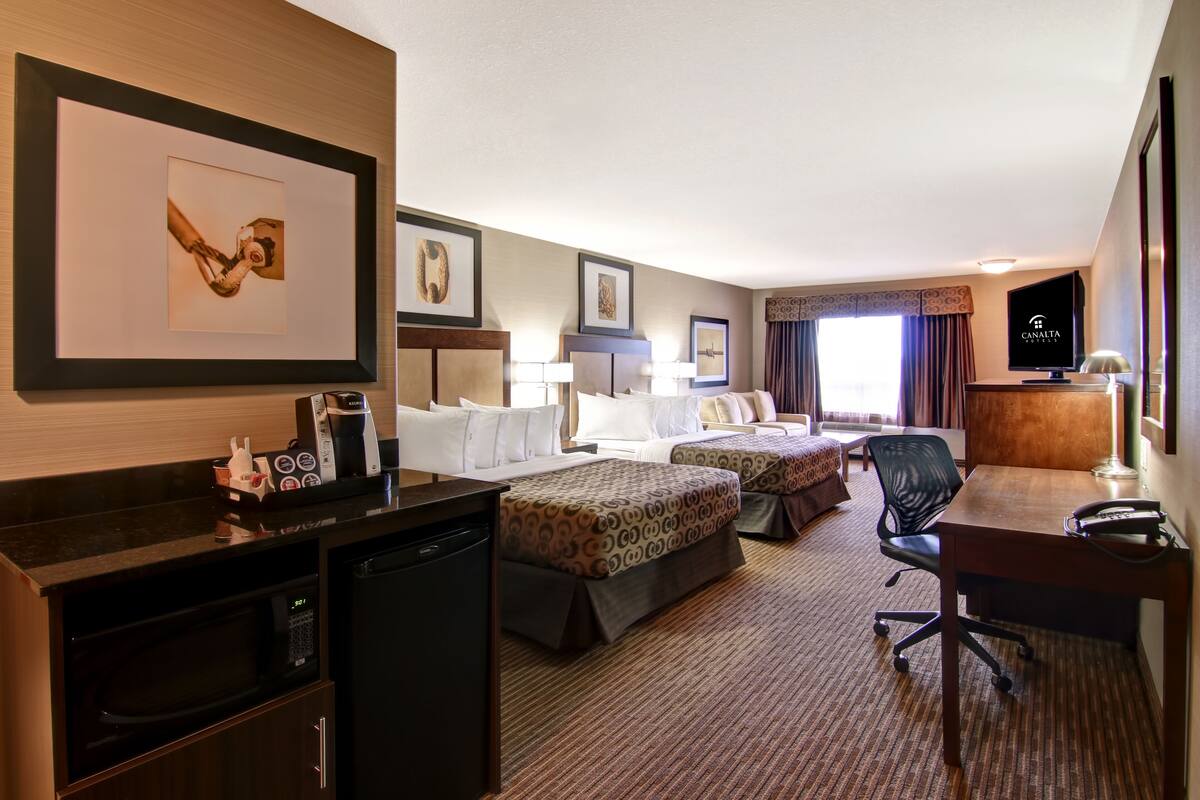 Habitación de hotel con dos camas, un escritorio, una silla, un televisor y un minibar.