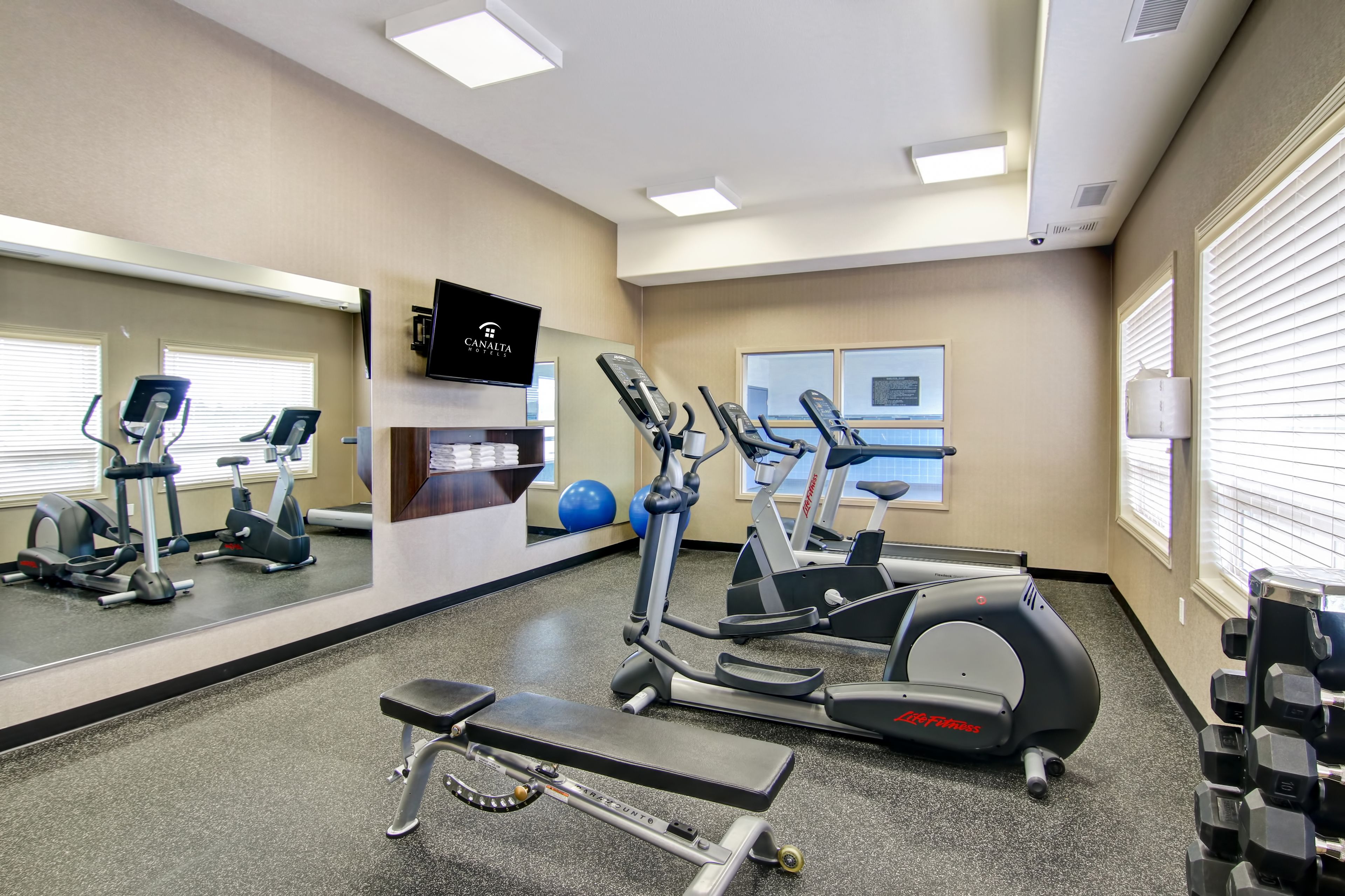 A gym with exercise equipment, a TV, and a mirror.