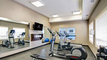A gym with exercise equipment, a TV, and a mirror.