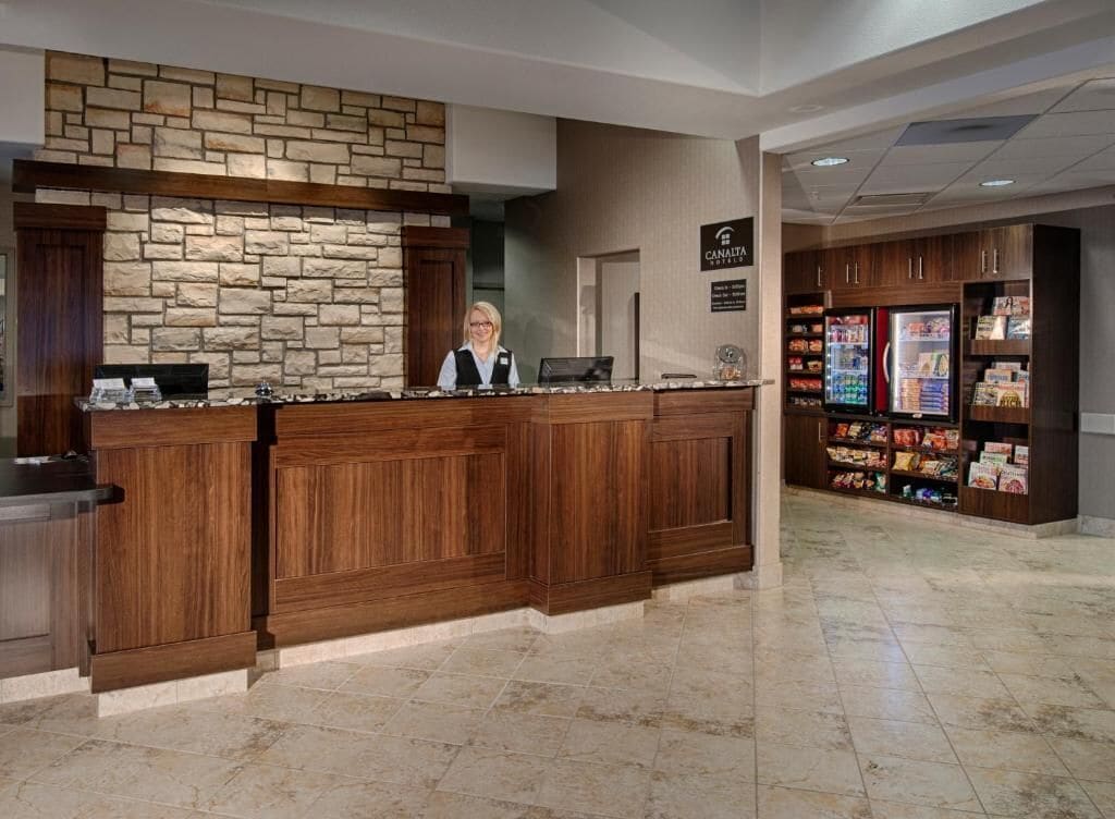Zona de recepción con pared de piedra, mostrador de madera y máquina expendedora.
