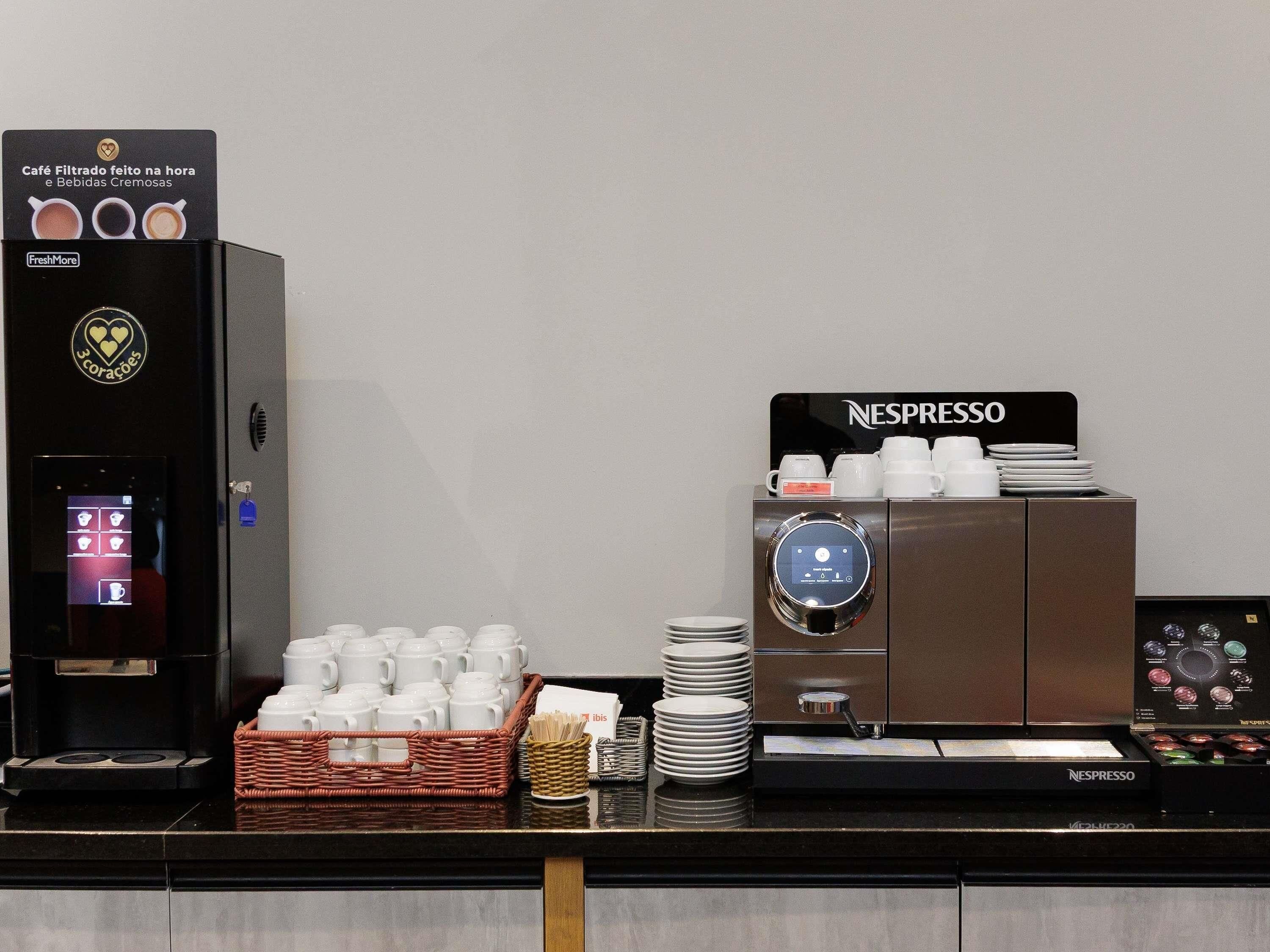 A coffee station with a FreshMore machine and a Nespresso machine, both equipped with multiple coffee cups and plates.