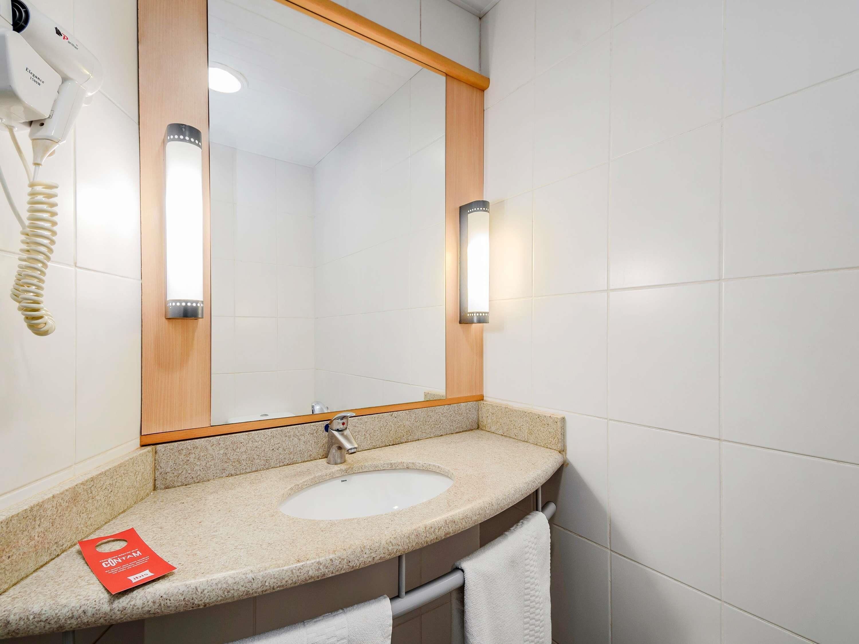 A bathroom with a white sink, a mirror with wooden frame, and a towel rack.