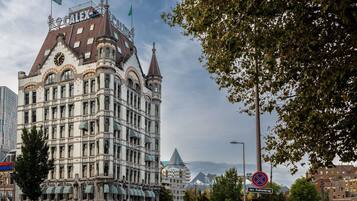 Un edificio histórico con una torre de reloj, rodeado de árboles y edificios modernos.