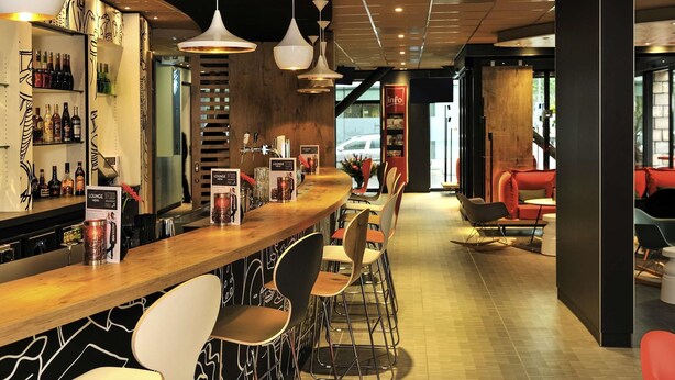 Un espace bar avec des tabourets, un comptoir et un présentoir à menus.