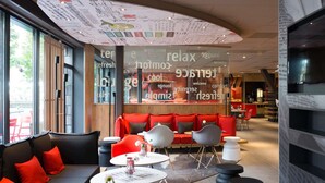 Un espace de détente moderne doté d’un plafond incurvé, de sièges rouges et d’un mur de verre sur lequel sont affichés différents mots.