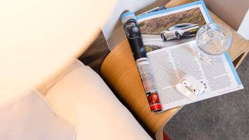 Una revista sobre una mesita de madera con una imagen de un coche, un bolígrafo y un par de auriculares.