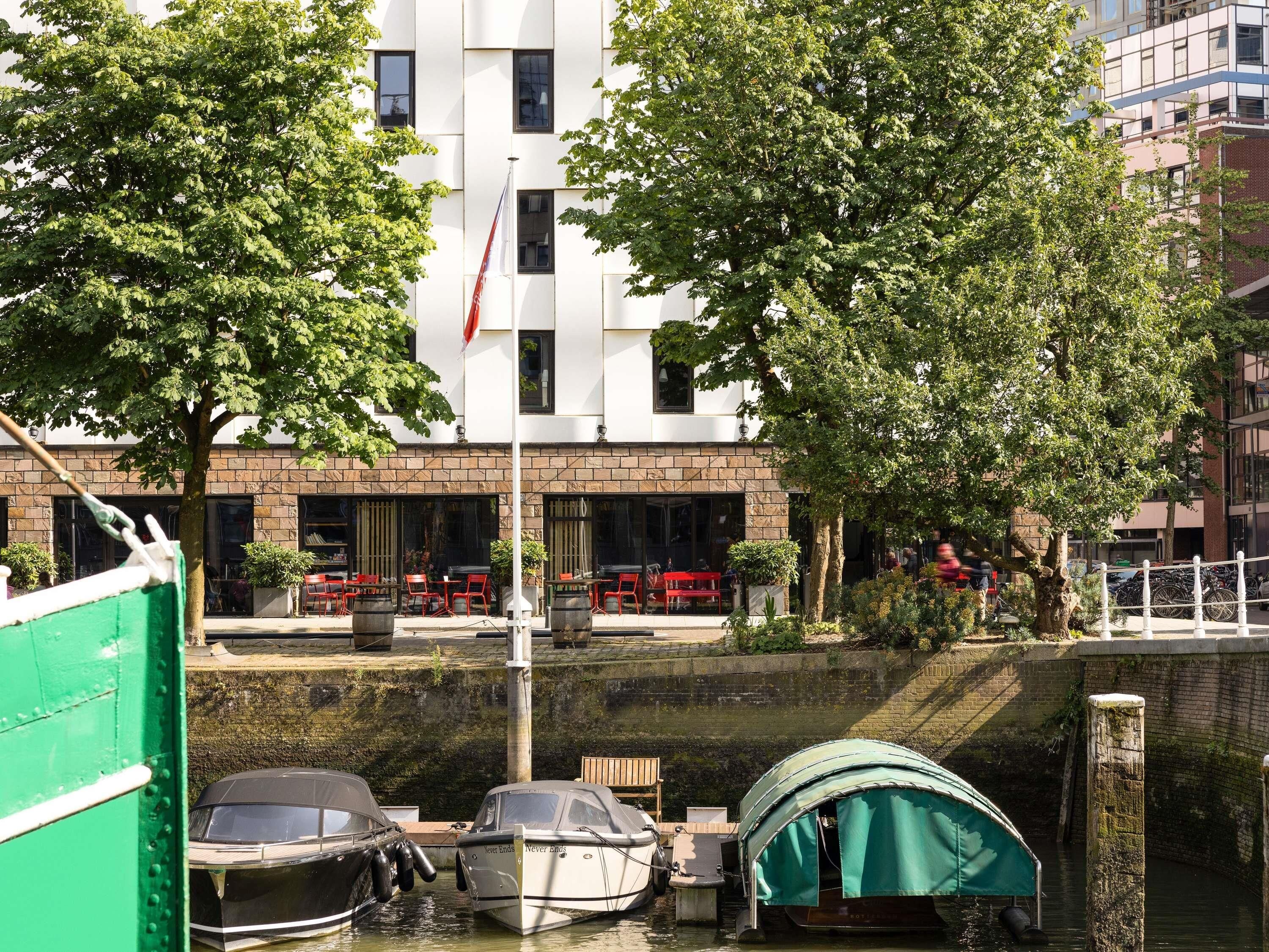 Hotel aan de rivier met terras, vlag en liggende boten.
