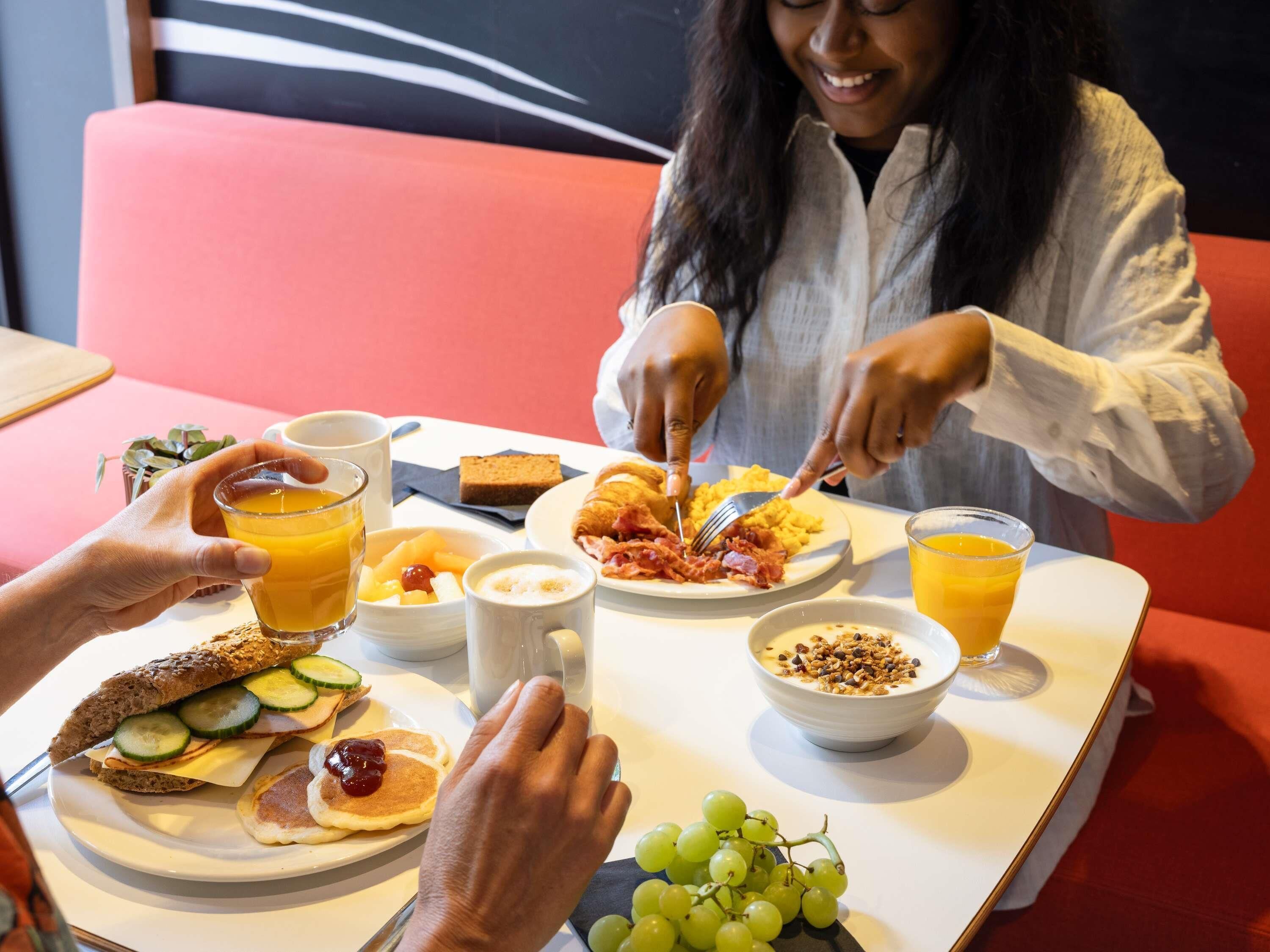 Ein Frühstückstisch mit Speisen und einer Person, die isst.