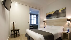 A modern hotel room with a large bed, two bedside tables, a TV mounted on the wall, and a painting above the bed. - THE 8 Boutique B&B (Barcelona)