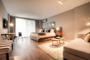 A modern hotel room with a bed, a sofa, a dining table, and a small coffee table. - CasaSur Bellini (Buenos Aires)