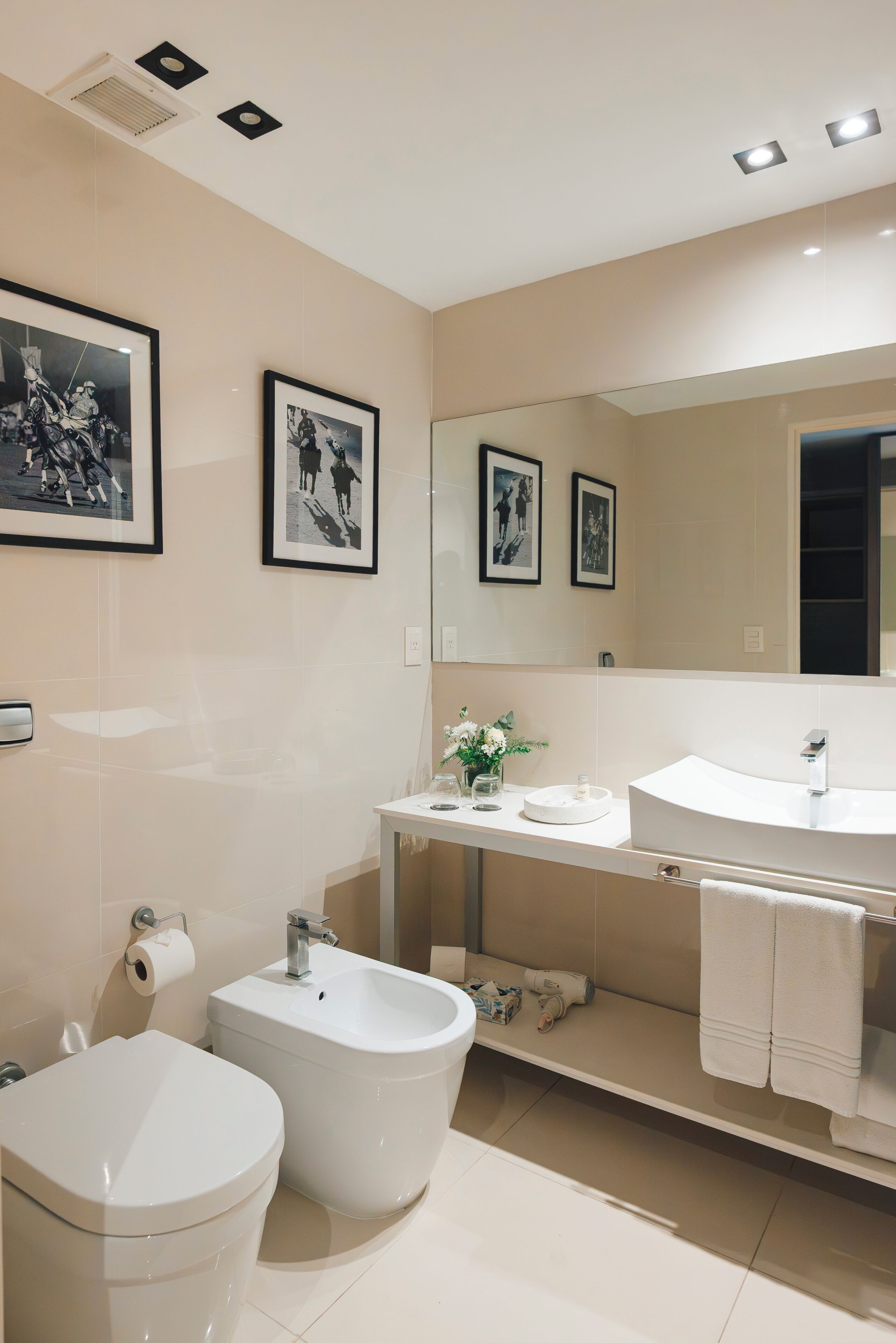 A modern bathroom with a toilet, bidet, sink, and mirror.