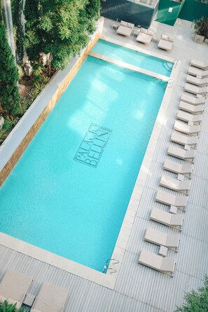 A rectangular pool with lounge chairs and a wooden deck.