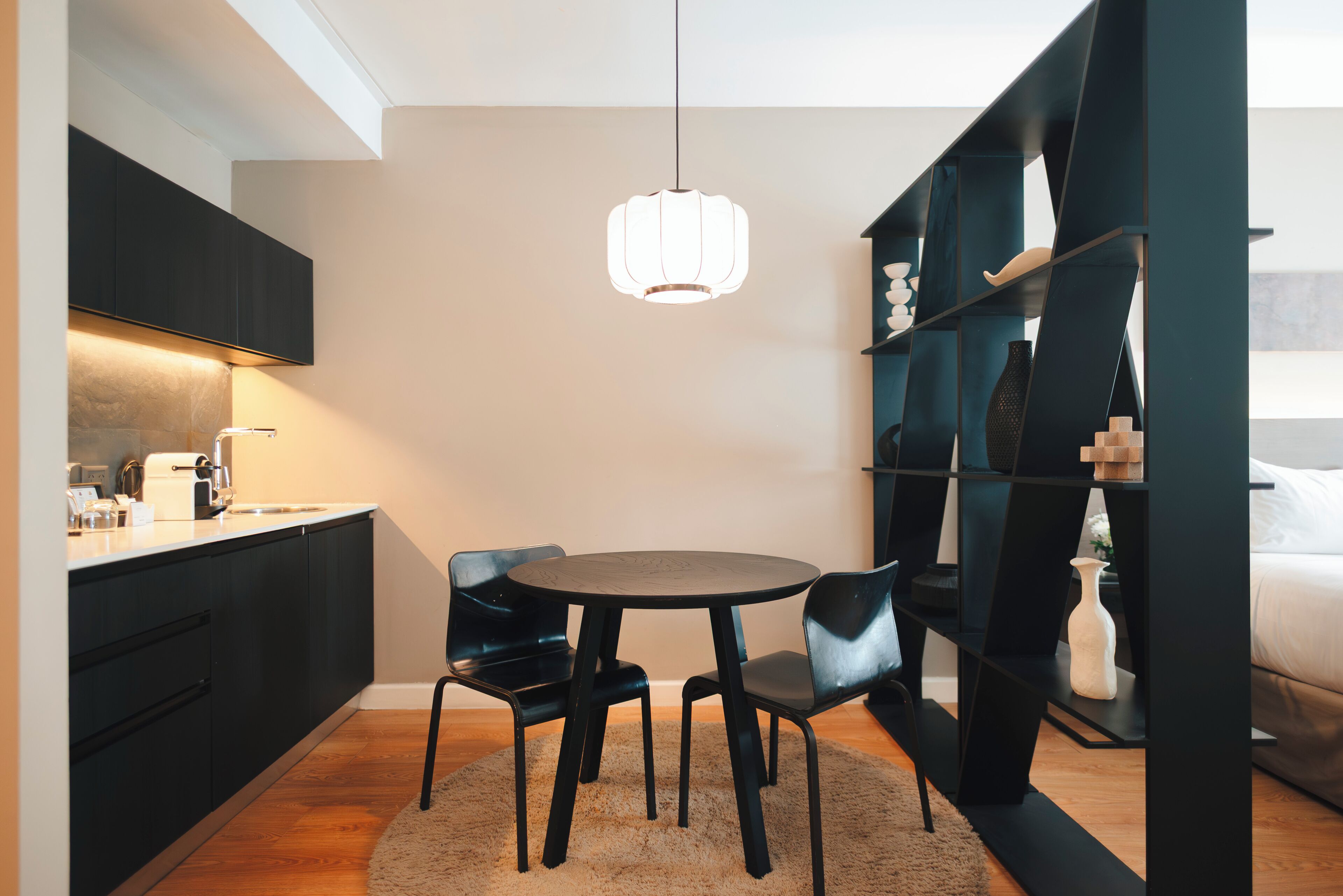A modern kitchen with dark cabinetry, a round table, and black chairs.