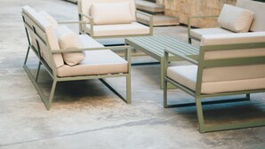 Outdoor seating with a concrete floor, surrounded by greenery and a building with large windows. - CasaSur Bellini (Buenos Aires)