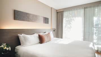 A hotel room with a large bed, a headboard, a wall-mounted artwork, and a window with curtains.