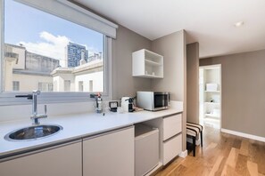 A modern kitchen with a built-in sink, a microwave, and a window with a view of buildings.