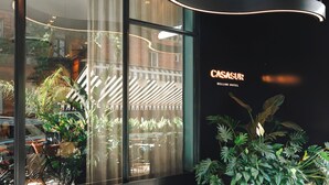 A modern hotel lobby with a curved seating area, large windows, and potted plants. - CasaSur Bellini (Buenos Aires)