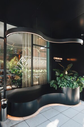 A modern hotel lobby with a curved seating area, large windows, and potted plants. - CasaSur Bellini (Buenos Aires)