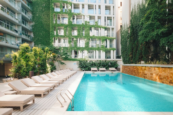 Una piscina al aire libre, sombrillas, tumbonas