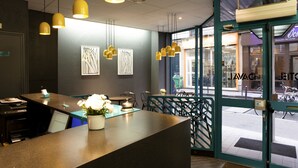 A modern interior with a reception desk, pendant lights, and artwork on the walls. - Hôtel Daval (Paris)